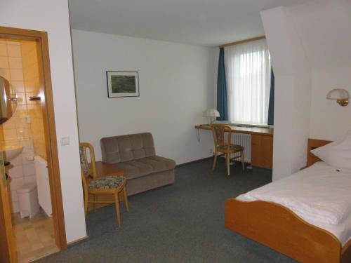 a hotel room with a bed and a couch and a desk at Gästehaus Krone in Oberndorf