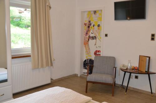 a room with a chair and a table and a television at GRÜNER HEINRICH - Bett&Frühstück in Oberaichwald