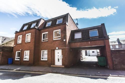 um grande edifício de tijolos com garagem numa rua em Mossie Apartment em Ayr