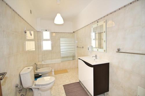 a bathroom with a toilet and a sink and a mirror at My Guest House in Portimão