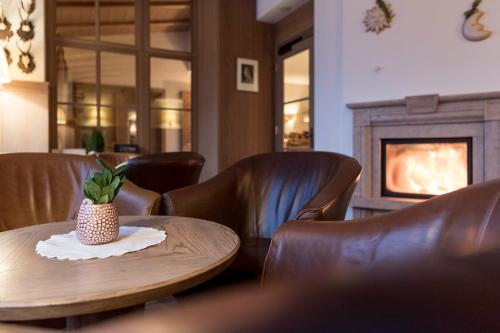 a room with a table and leather chairs and a fireplace at Hotel Gnollhof in Chiusa