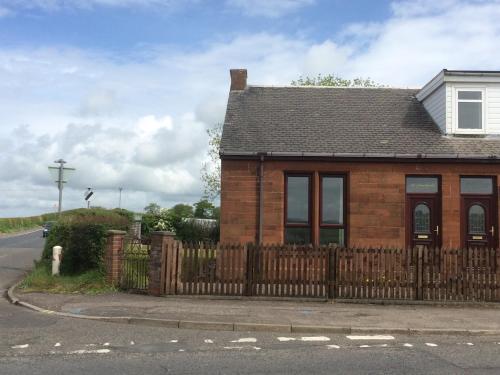 a house with a wooden fence in front of a street at Ayrshire cottage in Kilmarnock