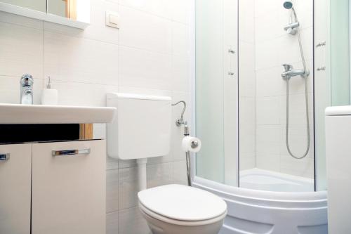 a white bathroom with a toilet and a shower at Dubravka apartmani in Mokošica