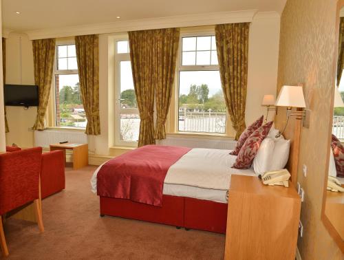 a hotel room with a bed and two windows at Wherry Hotel in Lowestoft