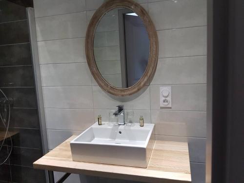 La salle de bains est pourvue d'un lavabo blanc et d'un miroir. dans l'établissement L'Ecrin du Lac, à Saint-Point-Lac