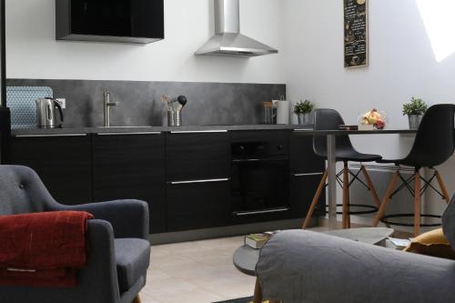 - une cuisine avec des placards noirs, un évier et une table dans l'établissement Le loft du Clos d'Esquay, à Esquay-sur-Seulles