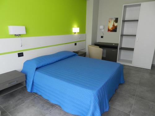 a bedroom with a blue bed and a green wall at Erasmus Hotel in Gela
