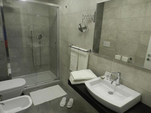 a bathroom with a sink and a shower and a toilet at Erasmus Hotel in Gela