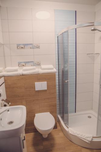a bathroom with a shower and a toilet and a sink at Hotel Duet in Człuchów