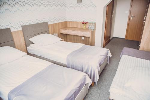 a hospital room with two beds with white sheets at Hotel Duet in Człuchów
