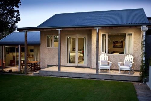 a house with two white chairs on a patio at For Puffed Pedallers in Mapua
