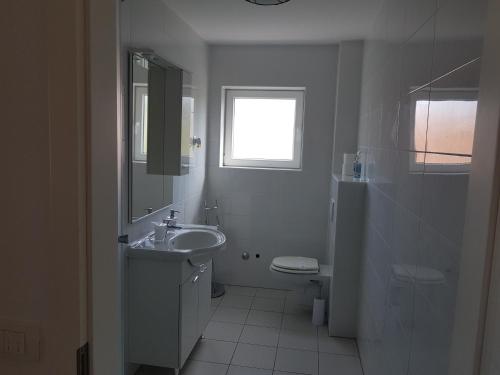 a white bathroom with a sink and a toilet at Pansion Marco Polo in Petrcane
