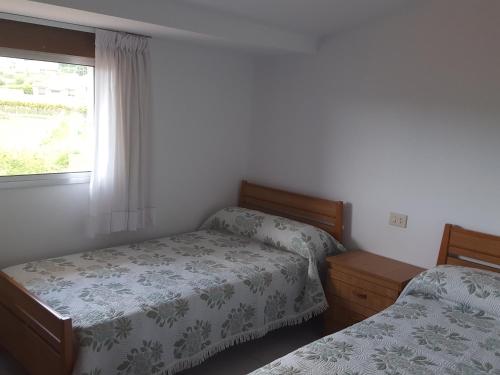 a bedroom with two beds and a window at Casa Artemia in Sanxenxo