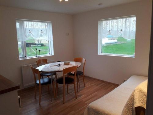 Habitación con mesa, sillas y 2 ventanas en Sandhaugar Guesthouse, en Kiðagil