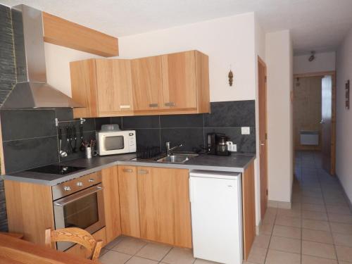 La cuisine est équipée de placards en bois, d'un évier et d'un four micro-ondes. dans l'établissement Les Serintes, à Saint-Léger-les-Mélèzes