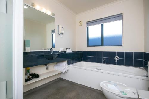 a bathroom with a tub and a sink and a toilet at ASURE Albert Park Motor Lodge in Te Awamutu