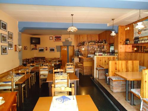 a restaurant with wooden tables and chairs and wine bottles at Hostal Porta De Núria in Ribes de Freser