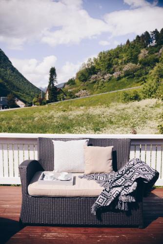 a wicker couch sitting on a deck with a view of a hill at Dalhus - House with jacuzzi in Norddal