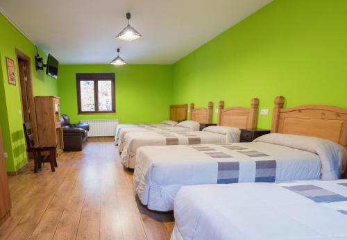 a room with four beds with green walls at Hostal Rural La Tintoreria in Villablino