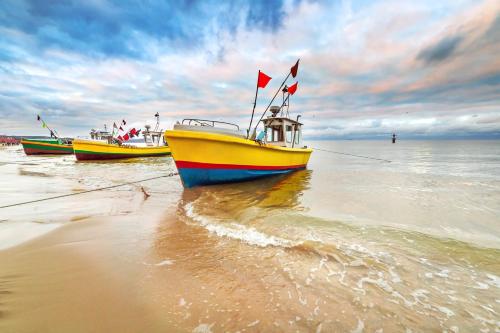 three boats sitting on the shore of a beach at Bursztynowa - Apartamenty przy Plaży in Gdańsk