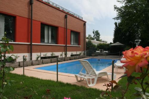 basen z 2 krzesłami obok budynku w obiekcie Airone Hotel w mieście Reggio nell'Emilia