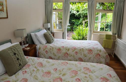 a bedroom with two beds and two windows at Town End Farm Cottages in Taunton