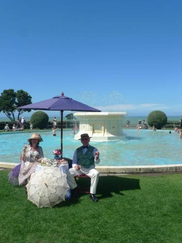 a man and woman sitting under an umbrella in front of a pool at Crashpalace Napier in Napier