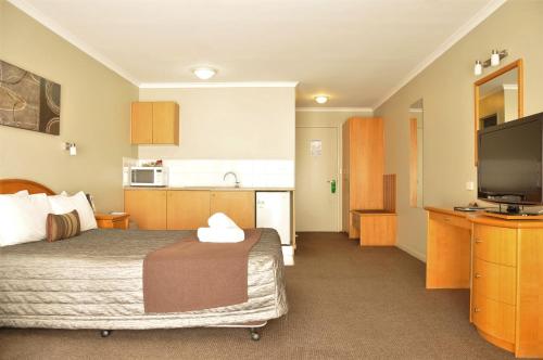 a hotel room with a bed and a flat screen tv at Chittaway Motel in Tuggerah