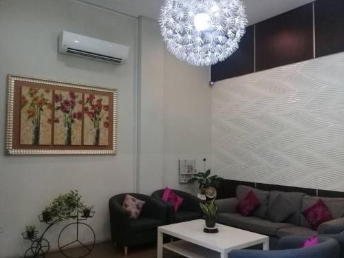 a living room with a couch and a chandelier at Ginasuite Hotel in Bandar Seri Begawan