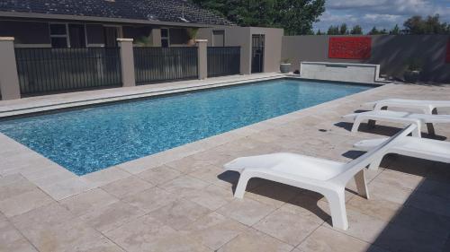 uma piscina com duas cadeiras brancas ao lado em Bathurst Gold Panner em Bathurst