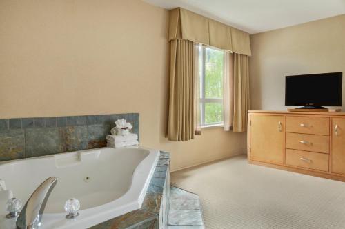 a large bathroom with a tub and a tv at Ramada by Wyndham Nanaimo in Nanaimo