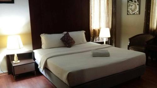 a bedroom with a large white bed with two lamps at Ginasuite Hotel in Bandar Seri Begawan