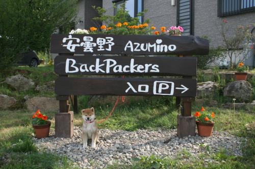 a dog on a leash standing under a sign at Azumino Backpackers 山の風 in Matsukawa