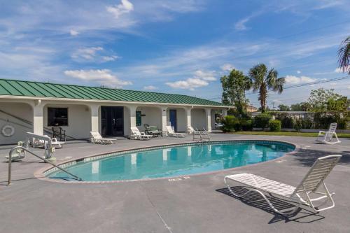 a swimming pool with chairs and a house at Motel 6 Waycross in Waycross