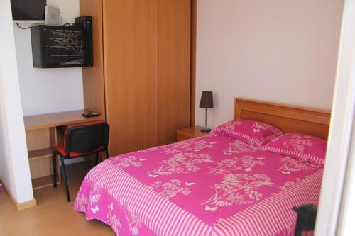 a bedroom with a pink bed and a desk at Apartamento António in Praia