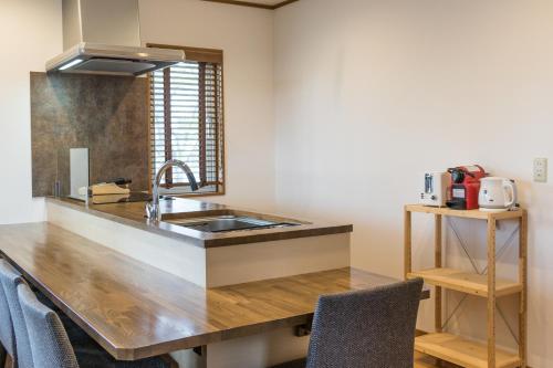 a kitchen with a sink and a counter with chairs at Kiseki in Niseko