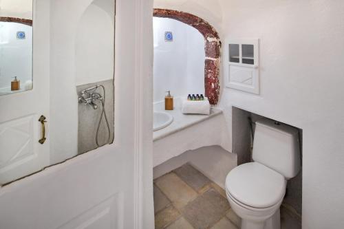 a bathroom with a toilet and a sink at Cosmoia Cave House in Oia