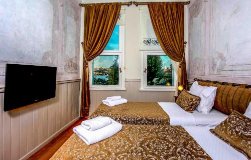 a bedroom with two beds and a flat screen tv at Hotel Troya Balat in Istanbul