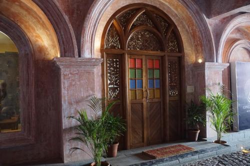 a large wooden door in a building with potted plants at Ginger House Museum Hotel in Cochin