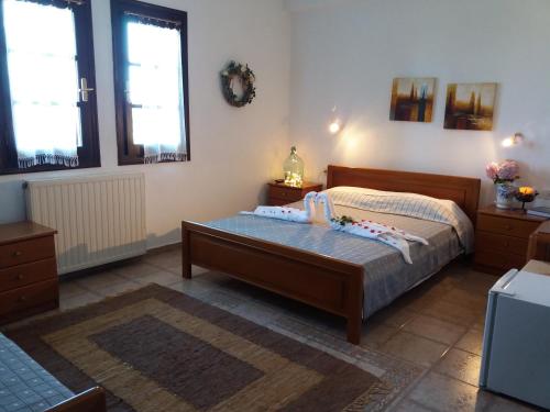 a bedroom with a bed and two windows at Dimosthenis Karastamatis Rooms in Xorychti