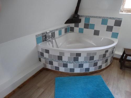 a bath tub in a bathroom with a blue rug at Le petit plessis in Ruaudin