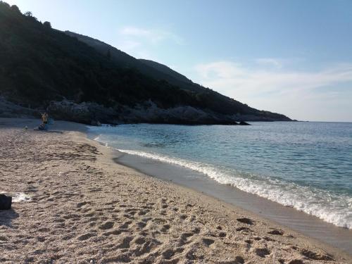 a person sitting on a beach next to the water at Dimosthenis Karastamatis Rooms in Xorychti