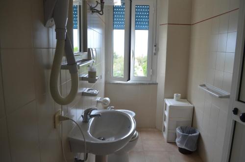 ein Bad mit einem Waschbecken und einem WC mit Fenstern in der Unterkunft Hotel Belmare in Marina di Grosseto