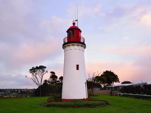 a red and white lighthouse sitting in a field at NRMA Portland Bay Holiday Park in Portland