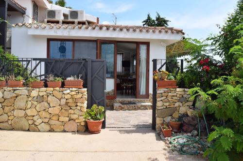 a house with a stone wall and a gate at Battistina Holiday Home in Costa Rei