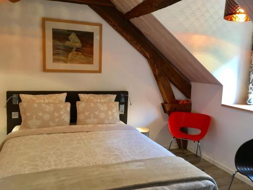 a bedroom with a bed and a red chair at Moulin de la Fayolle in Blot-lʼÉglise