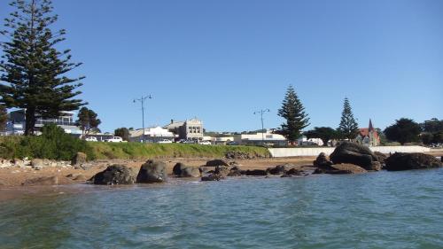 a body of water with rocks and a beach at The Madsen Boutique Hotel in Penguin