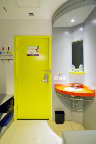 a yellow door in a bathroom with a sink at POP! Hotel Tebet Jakarta in Jakarta