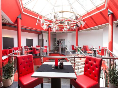 a red room with a table and red chairs at DORMERO Hotel Villingen-Schwenningen in Villingen-Schwenningen