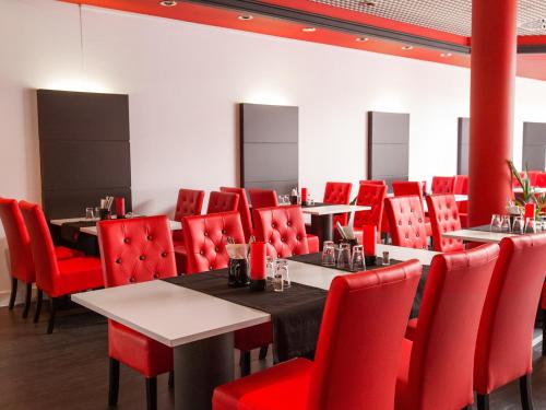 a dining room with tables and red chairs at DORMERO Hotel Villingen-Schwenningen in Villingen-Schwenningen